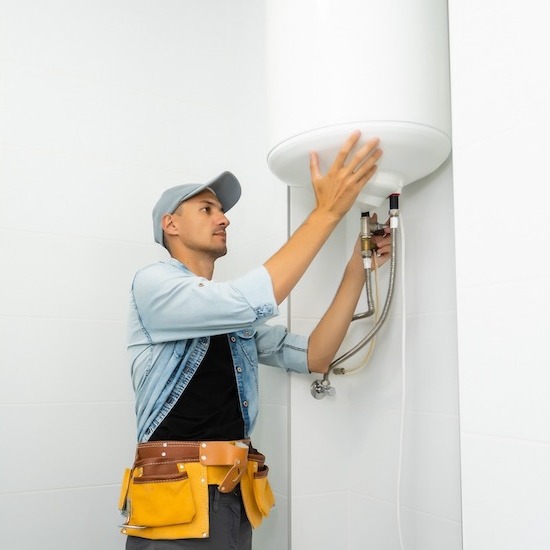 Plumber inspecting a large white tank water heater