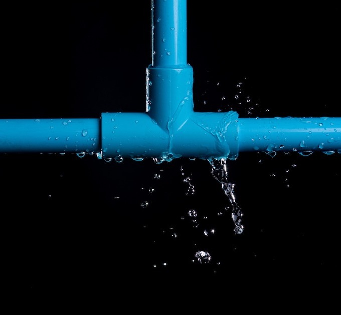 Leaky blue pipe with water streaming everywhere