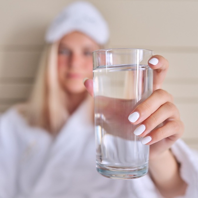 Pure filtered water in a clear glass held by a woman