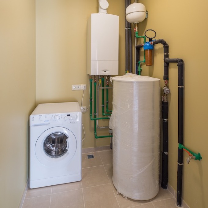 A residential washer/dryer next to water heaters