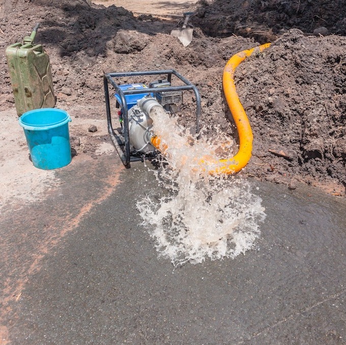 Main water line repairs depicted with machine pumping water out of pipeline